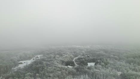 Eine-Drohnenansicht,-Die-Durch-Den-Nebel-Schneidet,-Um-Eine-Kleine-Stadt-Voller-Schnee-Zu-Enthüllen