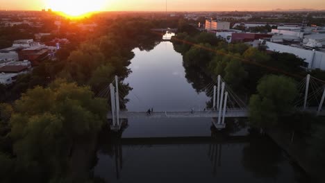 Aerial-view-over-people-walking-on-a-bridge-during-sunset-in-Culiacán-Rosales,-Mexico