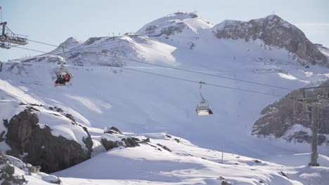 Ski-lifts,-chair-lifts-with-skiers-in-the-cold-alps,-Austria
