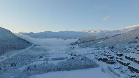 Cold-Myrkdalen-valley-during-early-morning-sunrise-with-frosty-haze-in-background---Aerial-besides-road-rv-13-looking-in-direction-of-Voss-and-Vinje-Norway-with-Vossestrand-hotel-to-the-right
