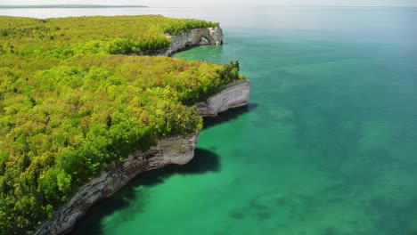 Aerial-Pan-Up-Coast-of-Sandstone-Rock-Cliffs-with-Sea-Arch,-Pictured-Rocks-National-Lakeshore,-Munising,-Michigan