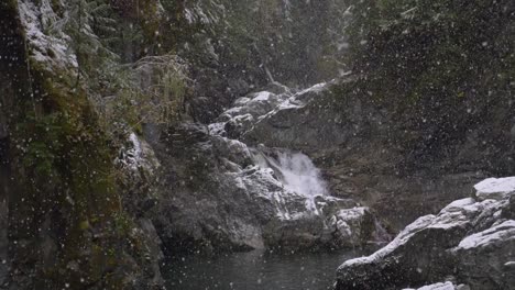 Filmische-Zeitlupe-Eines-Schnees,-Der-Auf-Den-Gebirgsfluss-Fällt