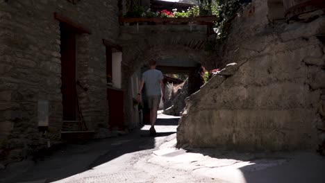 Man-in-shorts-and-a-t-shirt-walking-through-a-typical-old-Italian-alp-village