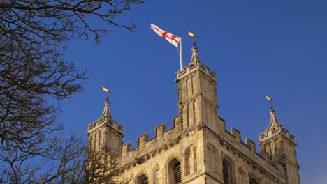 English-flag-flying-proudly-from-the-top-of-a-tower-against-a-brilliant-blue-sky