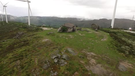 Casa-De-Campo-En-Montaña-Verde-Con-Turbinas-Eólicas