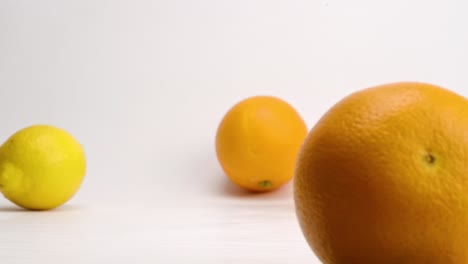 Bright-and-fresh-orange,-lemon-and-lime-citrus-fruits-falling-and-bouncing-on-white-backdrop-in-slow-motion