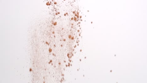 Chocolate-brown-cocoa-powder-ingredient-for-baking-raining-down-on-white-backdrop-in-slow-motion