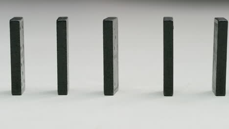 row-of-black-dominoes-in-a-white-studio