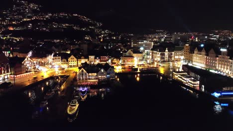 Forward-moving-aerial-with-tilt-up-during-night-at-fishmarket-and-downtown-Bergen