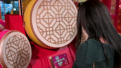 Eine-Frau-Spielt-Eine-Traditionelle-Trommel-Bei-Einer-Installation-Zum-Chinesischen-Neujahrsthema-Zum-Chinesischen-Neujahrsfest-In-Hongkong