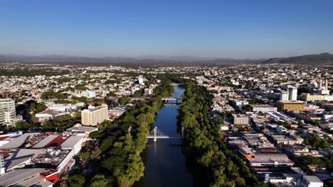 Aerial-view-over-bridges-on-the-Río-Tamazula-river,-golden-hour-in-Culiacan,-Mexico