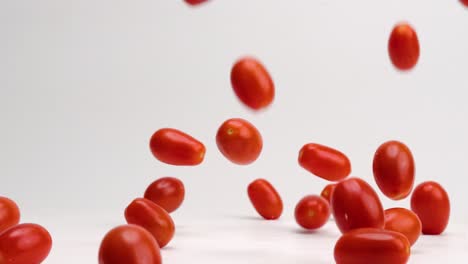 Fresh,-bright-red-cherry-tomato-fruits-and-vegetables-bouncing-on-white-table-top-in-slow-motion