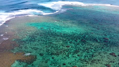 Aerial-view-of-waves-crashing-over-tropical-coral-reef-in-Kauai,-Hawaii,-USA