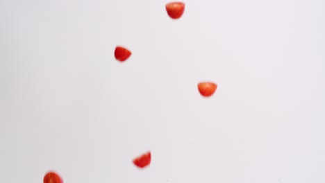 Fresh,-bright-red-halved-cherry-tomato-fruits-and-vegetables-raining-down-on-white-backdrop-in-slow-motion
