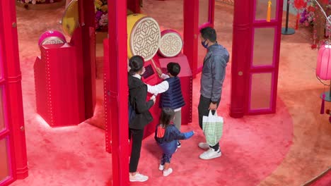 Ein-Junge-Spielt-Eine-Traditionelle-Trommel,-Während-Eine-Familie-Eine-Installation-Zum-Chinesischen-Neujahrsthema-Zum-Chinesischen-Neujahrsfest-In-Hongkong-Besucht