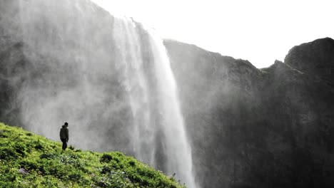 Atemberaubender-Blick-Auf-Den-Seljalandsfoss-Wasserfall-In-Island,-Auf-Den-Ein-Mann-Zugeht,-Um-Ihn-Näher-Zu-Betrachten