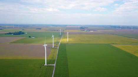 Aerial-view-flying-across-vast-Indiana-patchwork-farmland-and-spinning-alternative-energy-wind-turbines