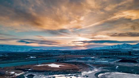 A-golden-sunset-with-snowy-mountains-and-a-valley-highway---aerial-hyper-lapse