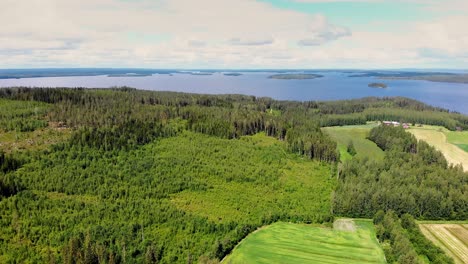 Vista-Aérea-De-La-Campiña-Y-El-Bosque-Finlandeses-Con-Un-Lago-E-Islas-Al-Fondo-En-Un-Día-De-Verano