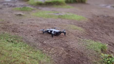 A-man-in-hiking-clothing-putting-a-black-drone-on-the-ground-to-take-off