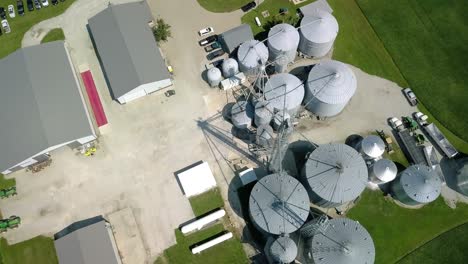Aerial-view-looking-down-over-industrial-Indiana-agribusiness-ranch-orbiting-steel-silo-storage-tanks
