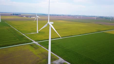 Umkreisende-Luftaufnahme-über-Windkraftanlagen,-Die-Blätter-Auf-Idyllischem-Grünem-Indiana-patchwork-ackerland-Drehen