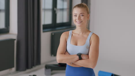 Young-blonde-woman-in-workout-clothes-smiles-at-camera,-half-body-shot