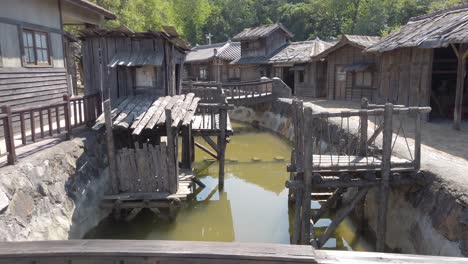 Walking-On-A-Small-Bridge-Over-A-Canal-With-Traditional-Houses-In-A-Korean-Village,-An-Old-Korean-Drama-Film-Set-In-Suncheon-City,-South-Korea