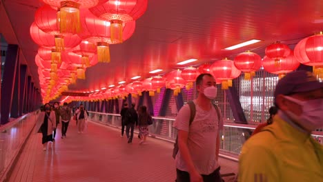 Fußgänger-Gehen-Durch-Eine-Fußgängerbrücke,-Die-Mit-Chinesischen-Laternen-Geschmückt-Ist,-Die-Von-Der-Decke-Hängen,-Um-Das-Chinesische-Neujahrsfest-In-Hongkong-Zu-Feiern