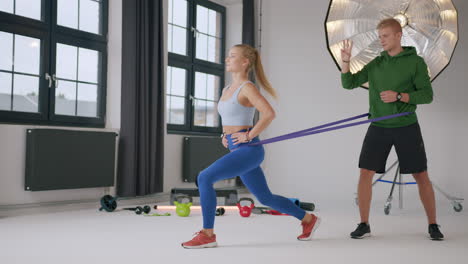 Young-fitness-couple-perform-lunges-using-a-resistance-band