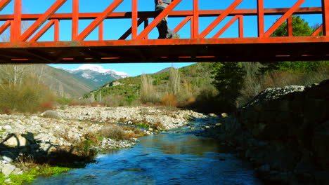 Aerial-view-of-a-man-walking-in-a-mountain-red-bridge-contemplating-the-landscape-of-the-Spanish-Pyrenees