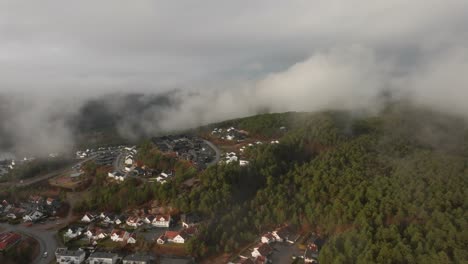 Drone-footage-of-housing-estate-in-Norway-with-some-fog-floating-in-th-air-and-sun-lighting-up-the-clouds