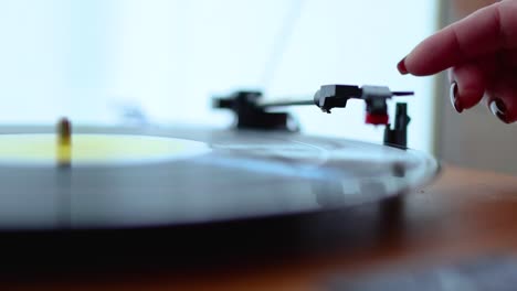 Close-up-of-woman-starting-up-an-old-record-player-with-a-vinyl-disc