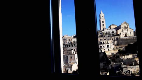 View-of-Matera,-Italy-through-a-window-with-video-panning-left-to-right