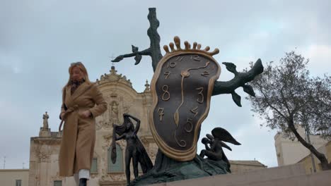 Escultura-De-Reloj-En-Matera,-Italia-Con-Una-Mujer-Posando-Para-Una-Foto
