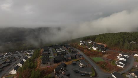 Drone-footage-of-housing-estate-in-Norway-with-some-fog-floating-in-th-air-and-sun-lighting-up-the-clouds
