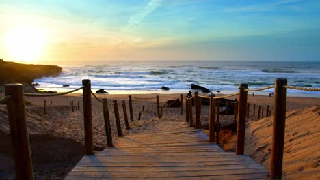 Vivid-Sunset-over-ocean-wooden-path-to-beach-in-Portugal-Atlantic-Guincho-coast,-near-Sintra-Estoril-Cascais-wide-shot