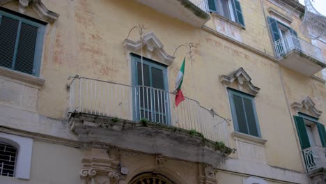 Italian-flag-hanging-over-balcony-in-Matera,-Italy-with-stable-establishing-shot