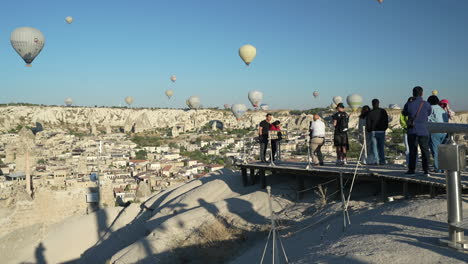 Touristen-Am-Aussichtspunkt-Mit-Blick-Auf-Heißluftballons,-Die-über-Der-Türkei-In-Kappadokien-Fliegen