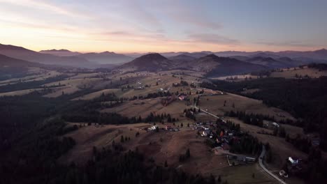 Aerial-view-of-picturesque-village-on-a-hill-with-pine-tree-forest-at-sunset