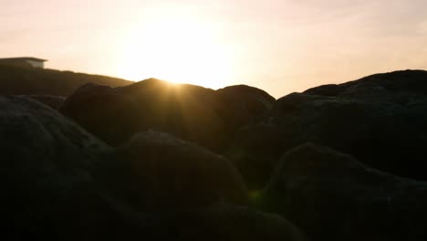 Sunset-lens-flares-on-Rocks-Edge-at-the-beach-during-epic-Dramatic-scenery-light-Geological