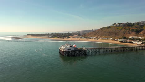 Aerial-of-historic-Malibu-Pier,-Pacific-Coast-Highway-and-the-Santa-Monica-Mountains-near-Los-Angeles-in-Southern-California
