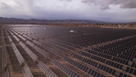 Aerial-Drone-Footage-of-Solar-Panel-Field-in-Joshua-Tree-National-Park-on-a-Sunny-Day-with-rainbow-in-the-background,-slow-vertical-tilt