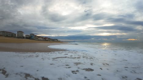 Low-altitude-flight-over-the-waves-at-the-surf-beach-of-Hossegor-during-a-cloudy-sunset