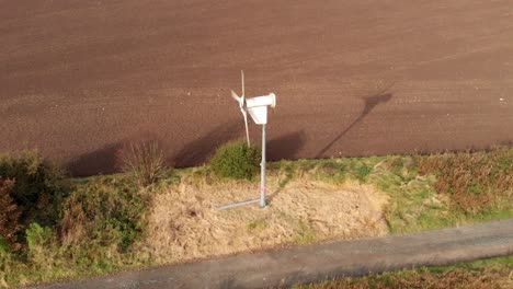 Small-wind-turbine-in-countryside-beside-path-on-the-outskirts-of-small-village