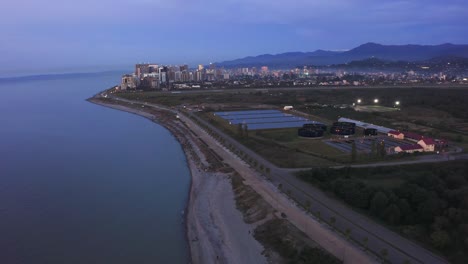 Cinematic-flight-above-sewage-treatment-facilities-on-the-seashore-at-dawn-after-colourful-sunset,-Batumi,-Georgia