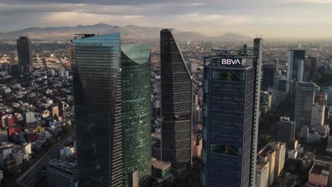 Aerial-View-of-Mexico-City-Towers-on-Reforma-Avenue-at-Sunrise-and-Cityscape-Skyline,-Cinematic-Drone-Shot