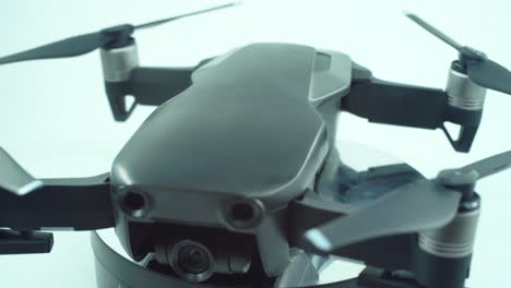 Close-up-shot-of-a-Drone-with-camera-lens-and-propellers,-silver-grey-color,-on-a-rotating-360-stand,-slow-motion,-4K-video