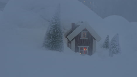 Fairytale-scene:-miniature-cabin-into-a-snow-with-pine-trees-surrounding-it