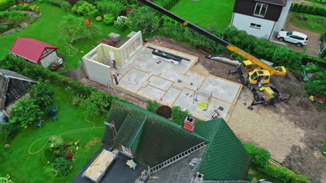 Industrial-crane-constructing-private-home,-aerial-fly-away-view